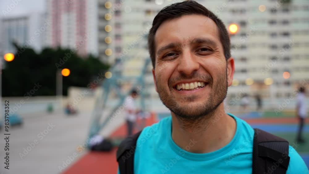 Man smiling at camera at Choi Hung Estate basketball court in Hong Kong, colorful and vibrant setting. Handheld Man smiling at camera at Choi Hung Estate basketball court in Hong Kong, colorful and vibrant setting. Handheld