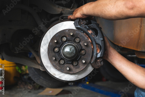 Auto mechanic installing car brake caliper and brake pads. 