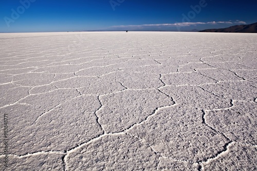 Foto A vast, cracked salt flat under a clear blue sky, showcasing a unique landscape