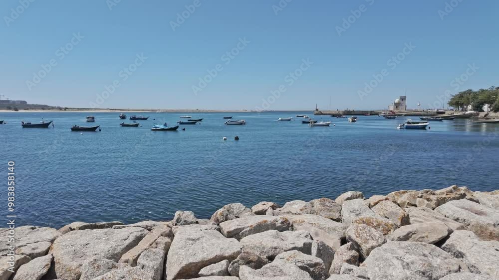 Small fishing boats floating in a calm blue sea with a rocky shore in Porto on a sunny day Small fishing boats floating in a calm blue sea with a rocky shore in Porto on a sunny day