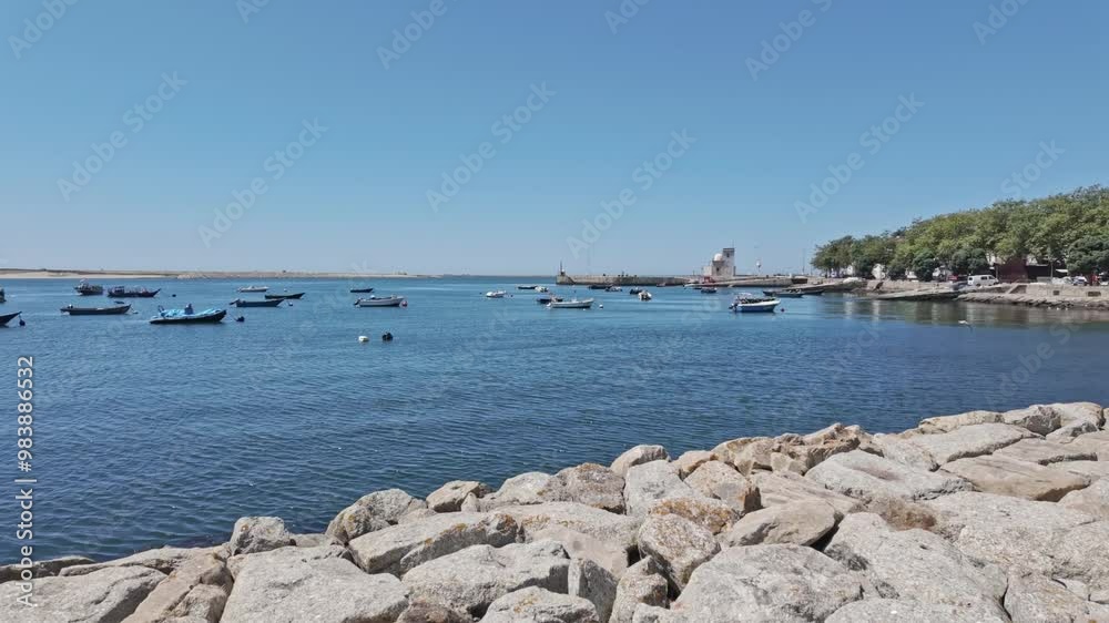 A quiet sunny day by the Porto waterfront with boats, trees, and a rocky path along the coast A quiet sunny day by the Porto waterfront with boats, trees, and a rocky path along the coast