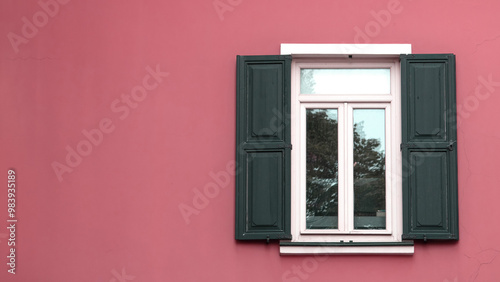 Window with wooden shutters on pink wall. Open shutter window. Exterior view of the building. Empty area.