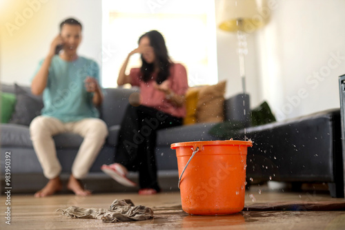 Water drips into buckets in living room as frustrated couple calling for insurance company
