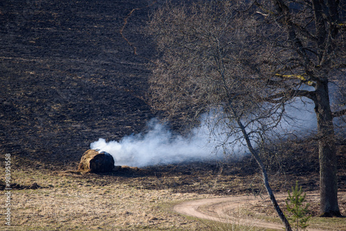 Burning last year's grass and hay roller at meadow. photo