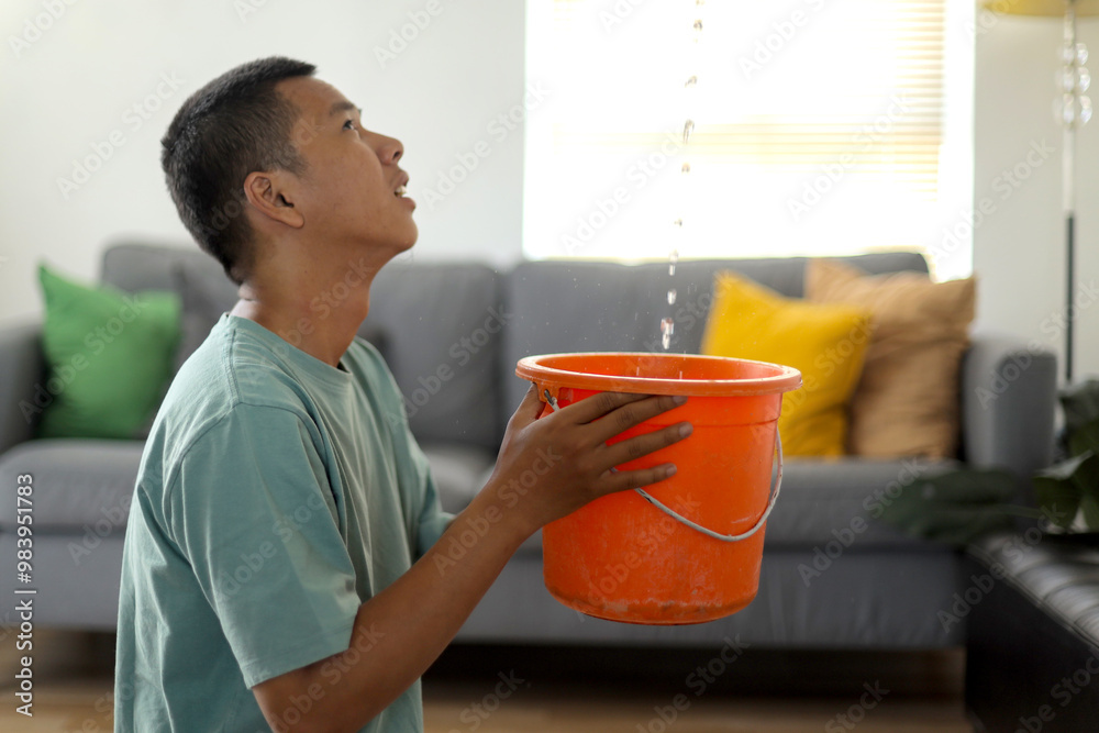 Upset Young Man Collecting Water Leaking and Dripping From the Ceiling
Upset Young Man Collecting Water Leaking and Dripping From the Ceiling