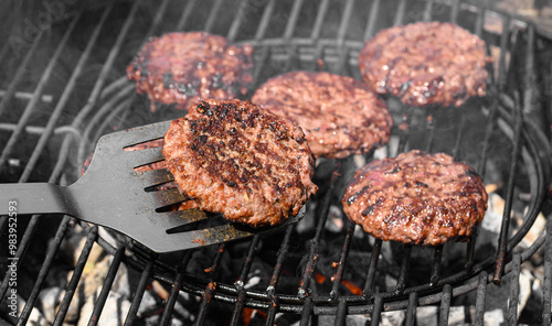 Piękne soczyste burgery wołowo-wieprzowe grillowane nad rozżarzonym węglem drzewnym na ruszcie 