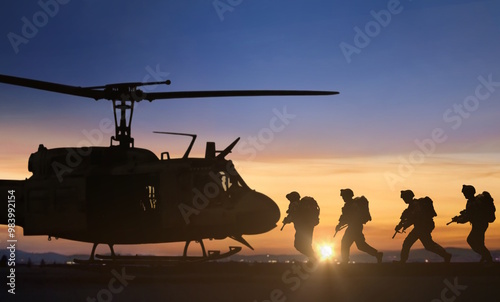 Special force unit running toward to boards military transport helicopter at sunset
