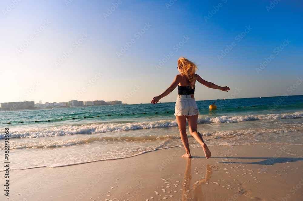 Very beautiful sky with the transition from blue to yellow over the sea. Back view of cheerful young woman with hands up. Freedom concept. Very beautiful sky with the transition from blue to yellow over the sea. Back view of cheerful young woman with hands up. Freedom concept.