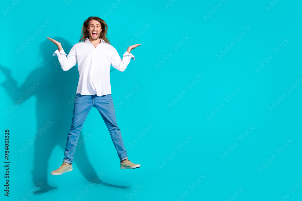 Full length photo of impressed good mood guy wear white shirt jumping high emtpy space isolated blue color background Full length photo of impressed good mood guy wear white shirt jumping high emtpy space isolated blue color background