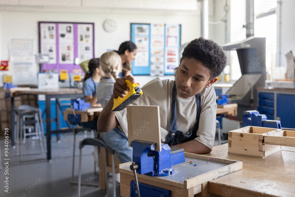 African American boy learning carpentry in woodworking class at school African American boy learning carpentry in woodworking class at school