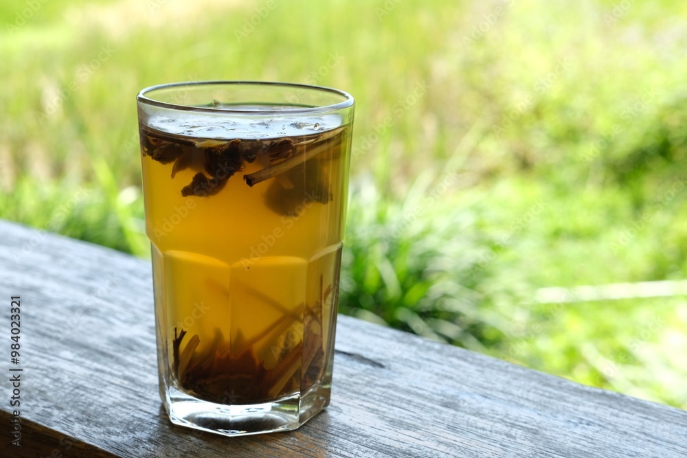 A refreshing glass of herbal tea with cinnamon sticks and spices, set against a blurred natural background. The golden liquid reflects sunlight, evoking warmth and tranquility in an outdoor setting. A refreshing glass of herbal tea with cinnamon sticks and spices, set against a blurred natural background. The golden liquid reflects sunlight, evoking warmth and tranquility in an outdoor setting.