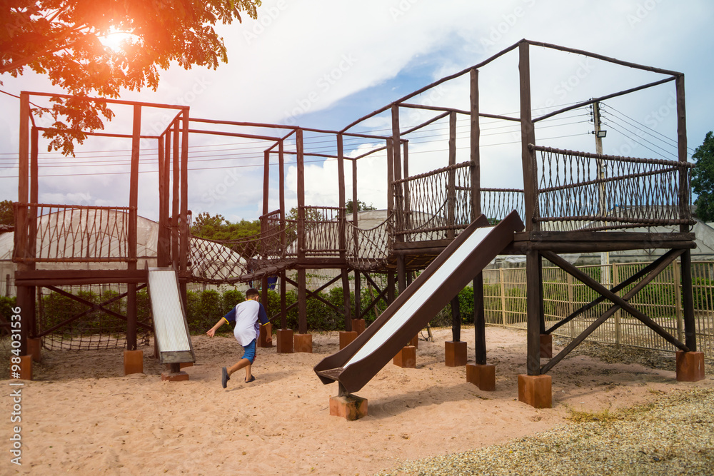 Children playground on sand yard activities in public park surrounded by green trees at sunlight morning. built climbing slide, seesaw on vintage playground. Children playground on sand yard activities in public park surrounded by green trees at sunlight morning. built climbing slide, seesaw on vintage playground.