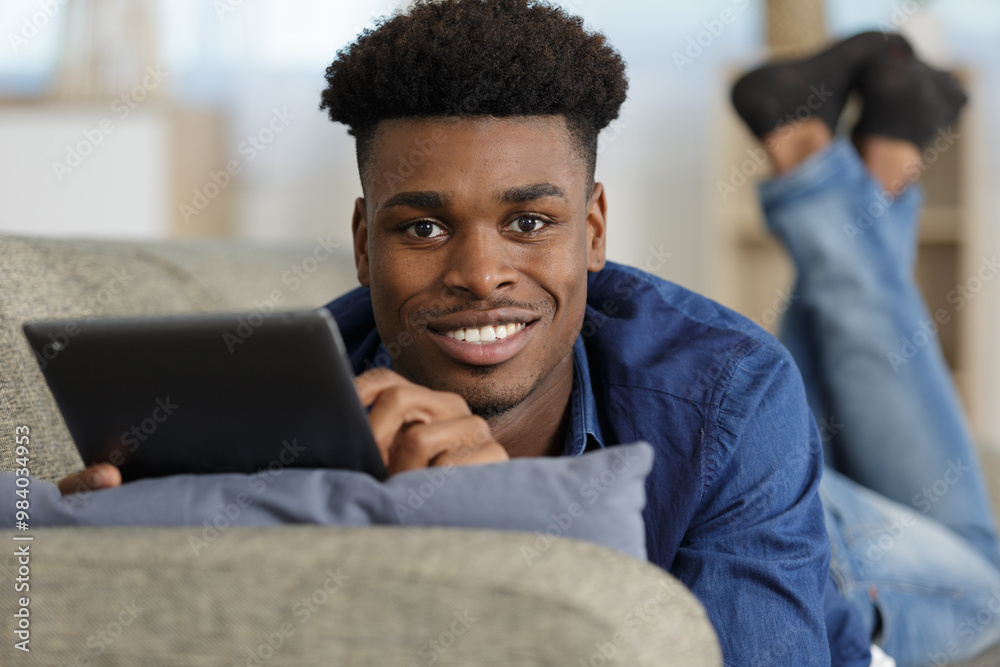 man holding a tablet laying on the sofa man holding a tablet laying on the sofa