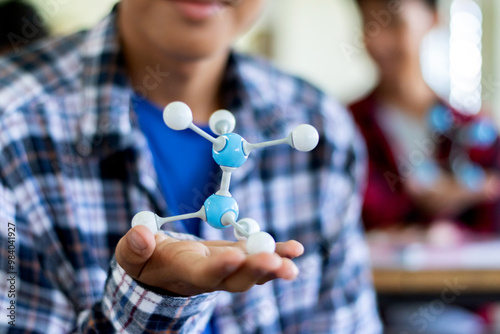 Student is studying simulate shape of covalent molecules by connecting molecular function shapes on the desk in Chemistry lesson, soft focus.