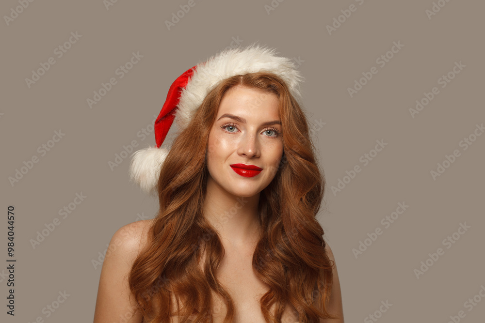 Beautiful Christmas woman in Santa hat with make-up and cute positive smile looking at camera, fashion portrait Beautiful Christmas woman in Santa hat with make-up and cute positive smile looking at camera, fashion portrait