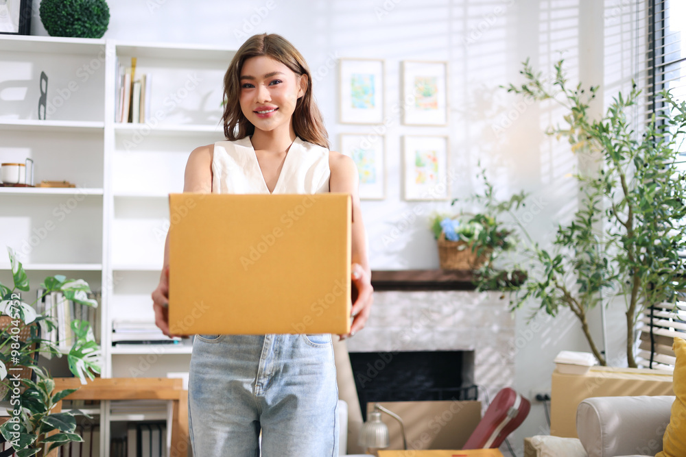 Happy young asian woman holding cardboard box preparing package for delivery to customer from selling online on internet from home. Happy young asian woman holding cardboard box preparing package for delivery to customer from selling online on internet from home.