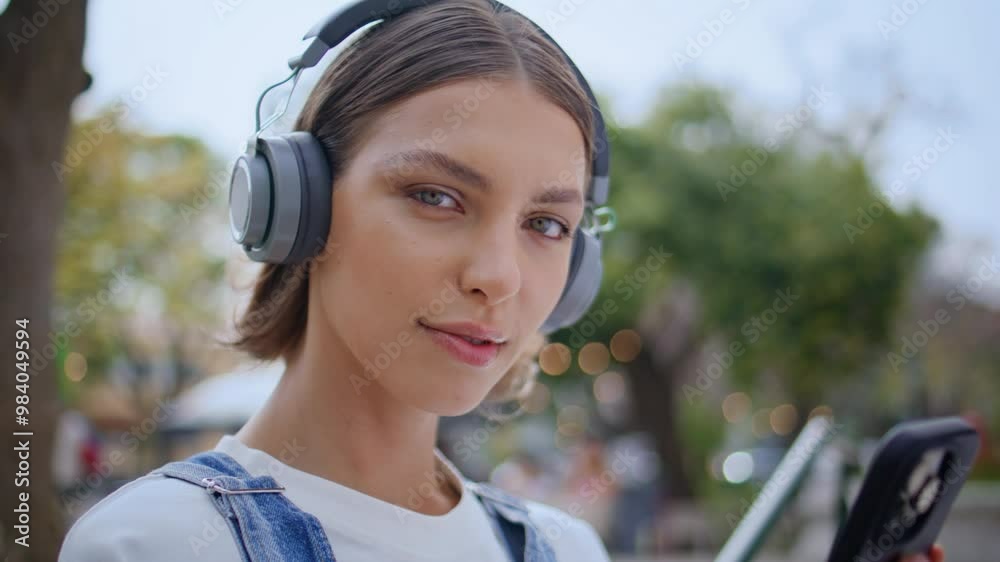 Girl posing street headphones holding mobile phone closeup. Woman listening song Girl posing street headphones holding mobile phone closeup. Woman listening song