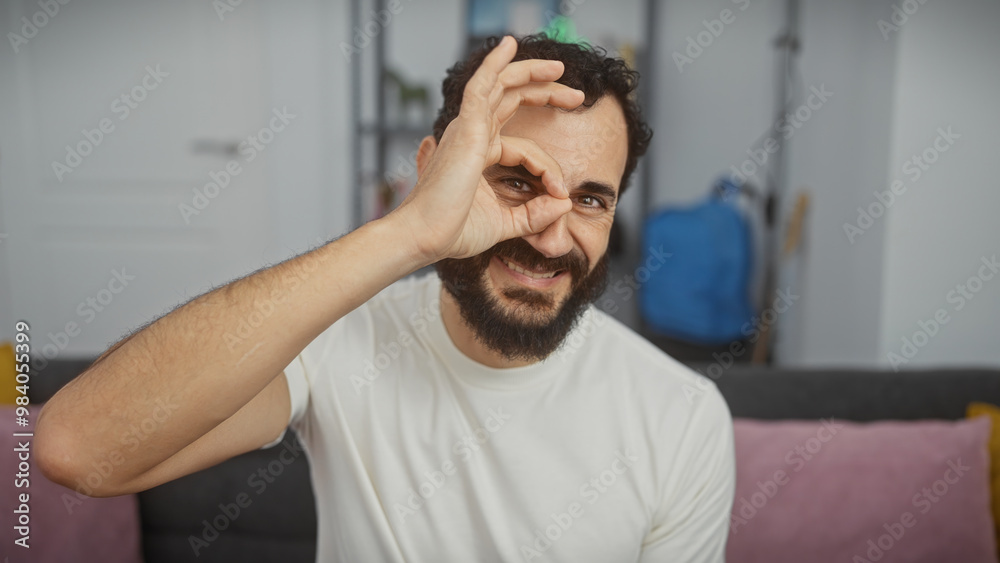 Obraz premium A smiling bearded man making ok gesture in a modern living room.