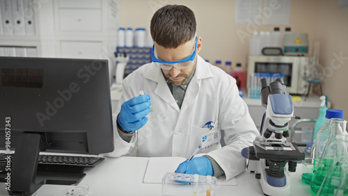 Handsome hispanic man in lab coat analyzing sample in science laboratory