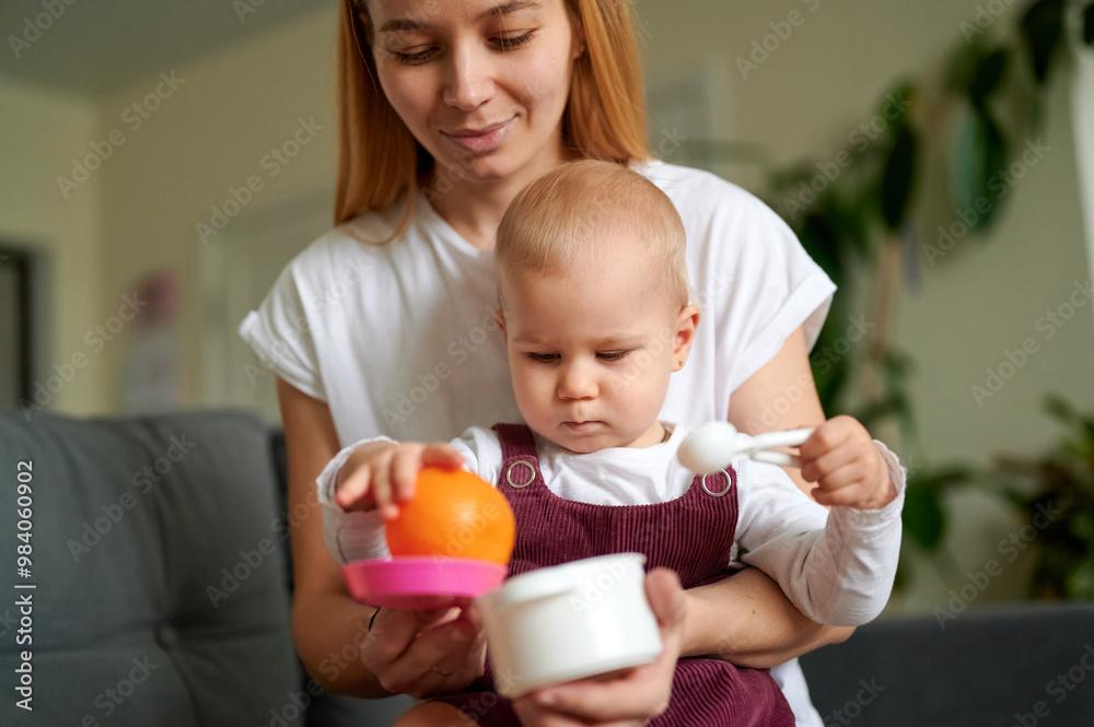 Caucasian mum and little blonde daughter role play with plastic utensils, vegetables and fruit in a domestic setting. Caucasian mum and little blonde daughter role play with plastic utensils, vegetables and fruit in a domestic setting.