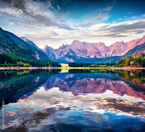 Hudge peak of Julian Alps reflected in the calm waters of Fusine lake. Majestic outdoor scene with Mangart peak on background, Province of Udine, Italy, Europe. Traveling concept background. photo