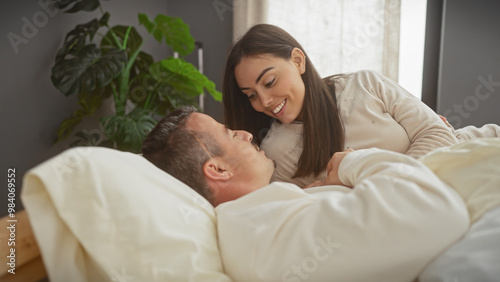 A loving couple enjoys a tender moment while relaxing together in a cozy bedroom setting, portraying intimacy and affection.