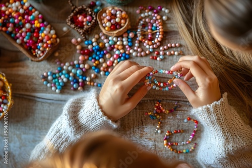 Smiling girl making a bracelet from beads. Making jewelry by hand photo