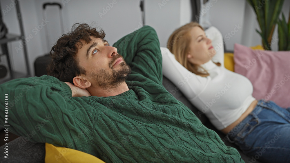 A contemplative man and woman relaxing together in a cozy, modern living room, depicting family intimacy. A contemplative man and woman relaxing together in a cozy, modern living room, depicting family intimacy.