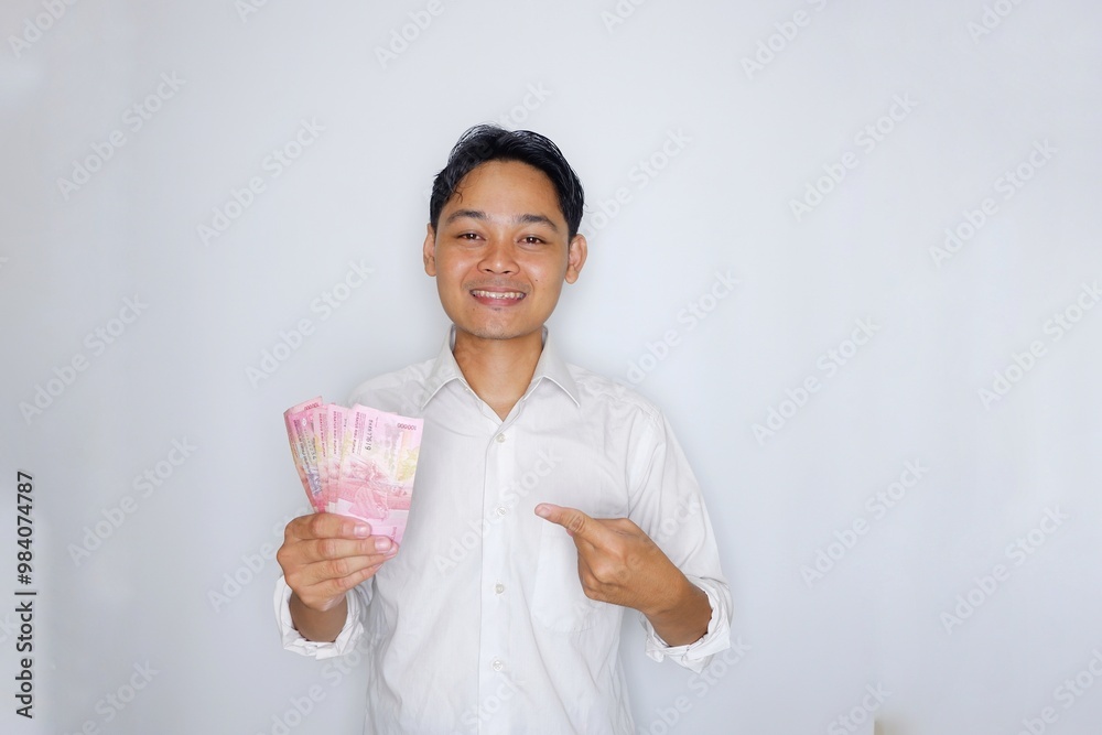 Random expression of adult Asian Indonesian man while holding banknotes isolated on white background Random expression of adult Asian Indonesian man while holding banknotes isolated on white background