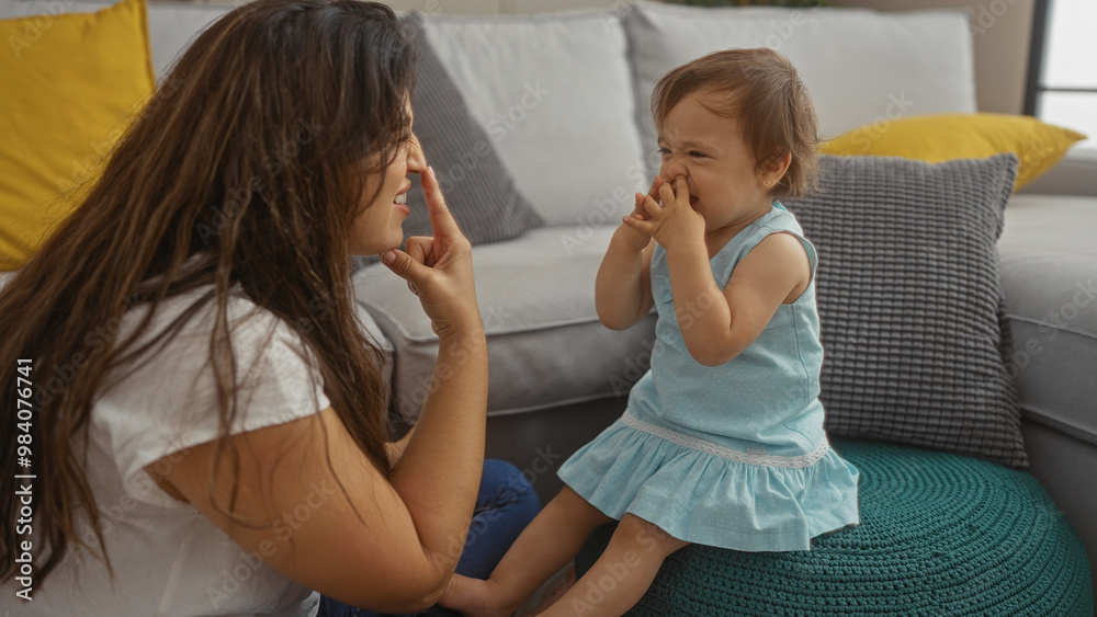 Mother and toddler daughter touch noses and laugh together in a cozy living room, creating a tender family moment filled with love and joy. Mother and toddler daughter touch noses and laugh together in a cozy living room, creating a tender family moment filled with love and joy.
