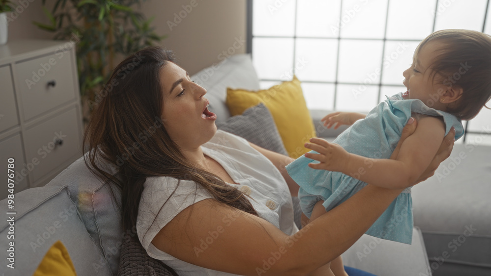 Fototapeta premium Woman playing with baby girl in living room showcasing family love and togetherness at home