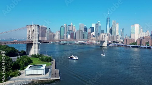Drone aerial landscape of yacht ship ferry passing under Brooklyn Bridge New York City CBD Skyline Manhattan USA America East River infrastructure buildings skyscrapers