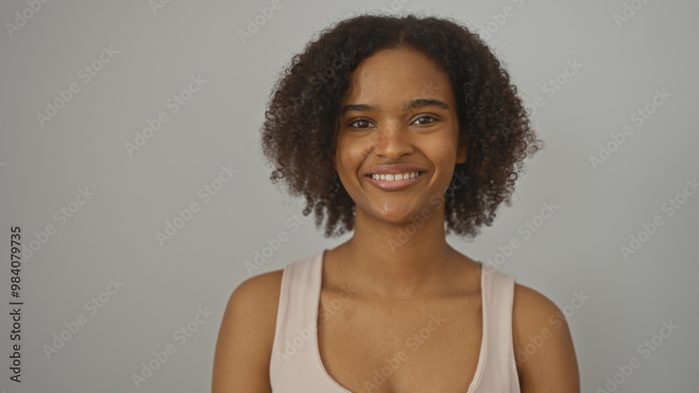 A beautiful young african american woman with curly hair smiles confidently over an isolated white background. A beautiful young african american woman with curly hair smiles confidently over an isolated white background.