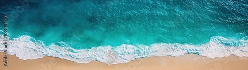 Aerial view of a pristine beach with turquoise waves crashing gently on the sandy shore, showcasing the beauty of coastal nature.