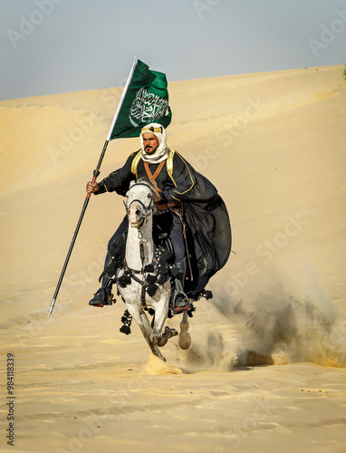 Arabian Warrior, riding his white stallion with Saudi Arabian flag in the empt quarter desert photo