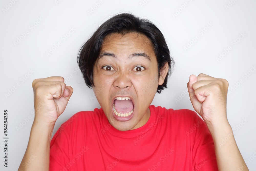 Portrait of an Indonesian man with long hair with a headband and red shirt celebrating Indonesian Independence Day with high nationalism on an isolated white background
