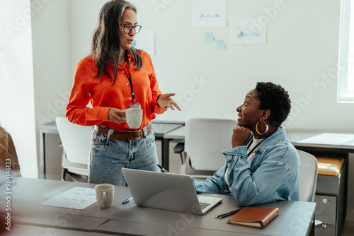 Women colleagues discussing project ideas together in a modern office