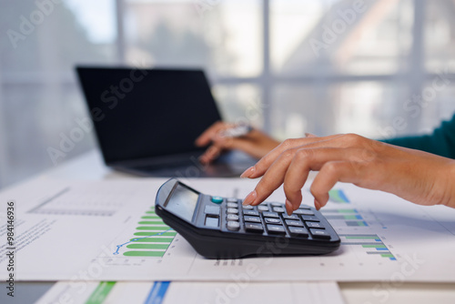 Close up of female hand accountan using a laptop computer and calculator to calculate taxes at desk in the office financial business, calculating accounting online marketing.