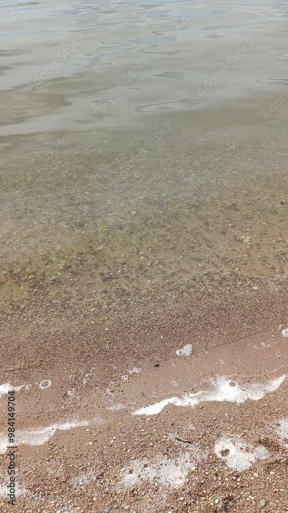 Small waves hit the shore of the sea or river or lake. Clouds are reflected in clear water. Pebble coast. A jet ski floats quickly along the shore Small waves hit the shore of the sea or river or lake. Clouds are reflected in clear water. Pebble coast. A jet ski floats quickly along the shore