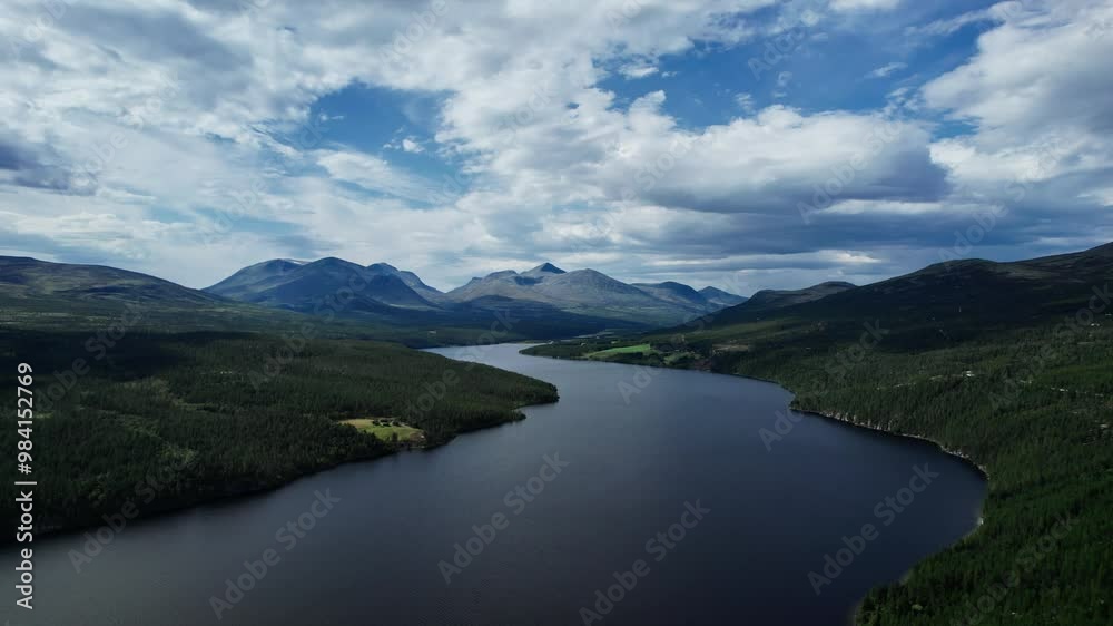 Discover the breathtaking beauty of Rondane National Park with an aerial view showcasing a serene lake surrounded by towering mountains and lush greenery under a dynamic sky in Norway Discover the breathtaking beauty of Rondane National Park with an aerial view showcasing a serene lake surrounded by towering mountains and lush greenery under a dynamic sky in Norway