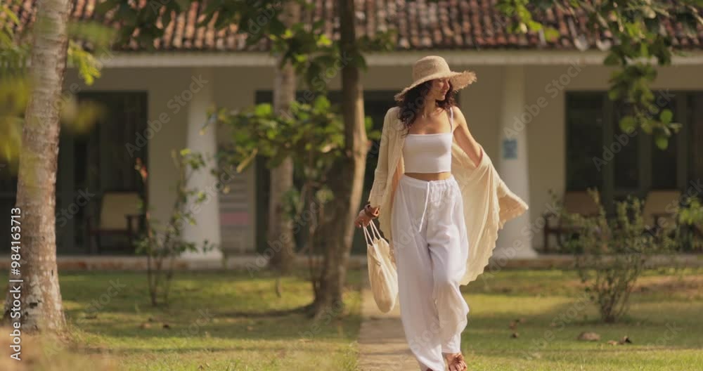 Elegant Woman in Trendy Summer Outfit Walking Through Resort Garden Elegant Woman in Trendy Summer Outfit Walking Through Resort Garden