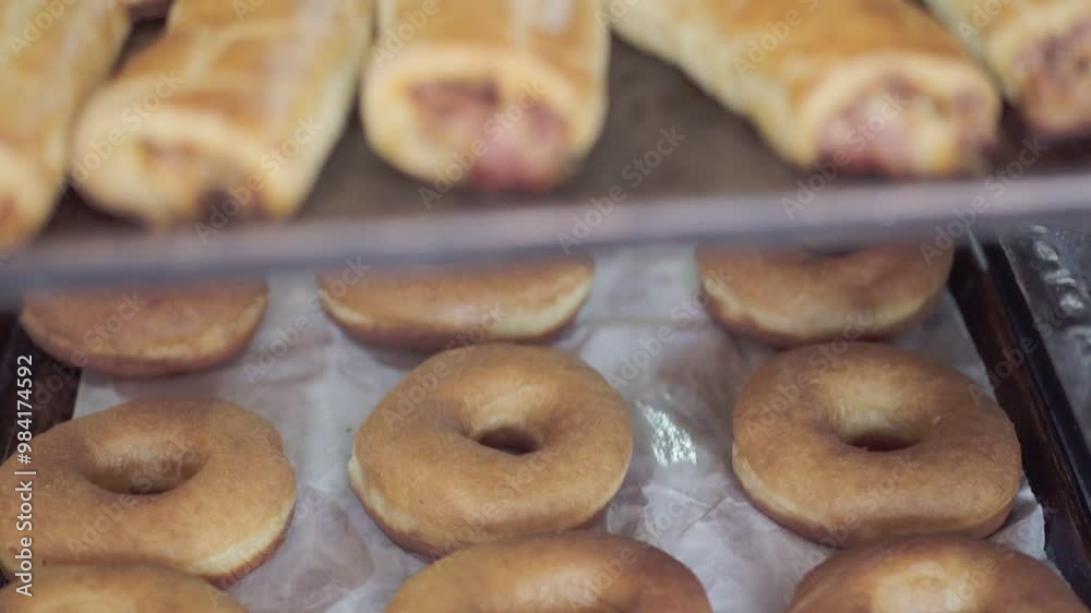 A variety of freshly baked donuts and pastries resting on racks in a bakery, ready to be served. A variety of freshly baked donuts and pastries resting on racks in a bakery, ready to be served.