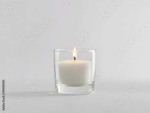 Small white candle burning inside a clear glass holder mock up isolated on white background