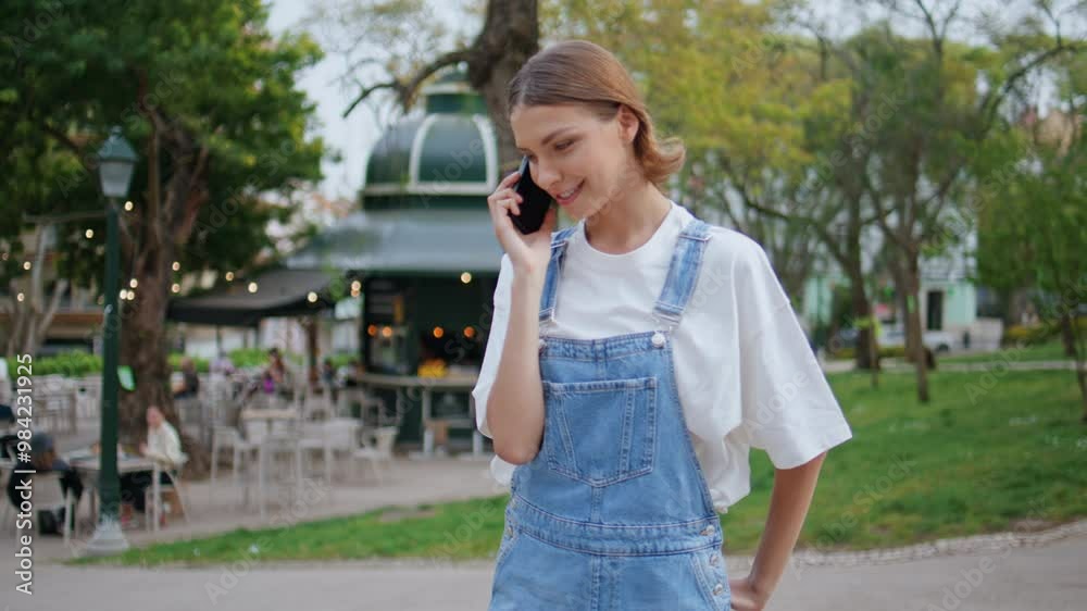 Smiling teenager talking cellphone strolling park alley. Positive woman enjoy Smiling teenager talking cellphone strolling park alley. Positive woman enjoy