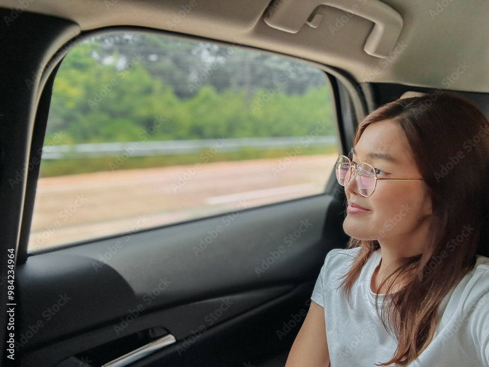 Happy asian Thai woman sitting at back as passenger while traveling by car on road in Thailand, looking out side the window. Happy asian Thai woman sitting at back as passenger while traveling by car on road in Thailand, looking out side the window.