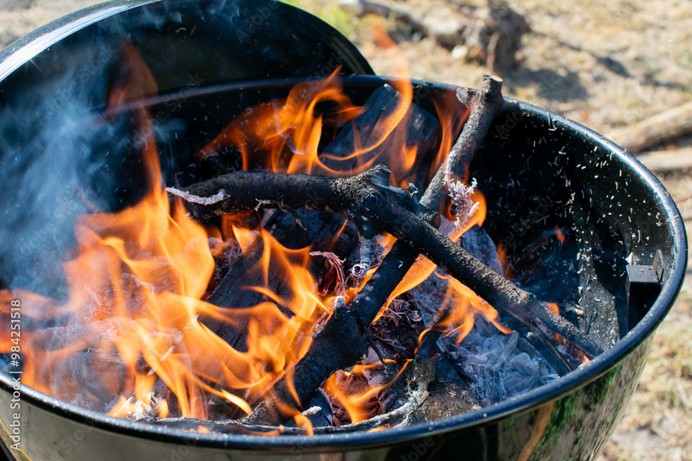Vivid flames and smoldering wood in a barbecue grill, ideal for summer cookouts and outdoor gatherings Vivid flames and smoldering wood in a barbecue grill, ideal for summer cookouts and outdoor gatherings