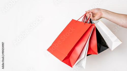 Hand holding colorful shopping bags on white background, perfect for illustrating Black Friday sales or retail shopping concepts