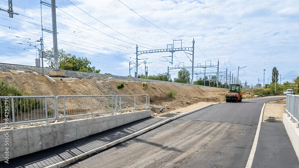 Naklejka premium Road construction near railway tracks highlighting infrastructure development and transportation improvements on a sunny day