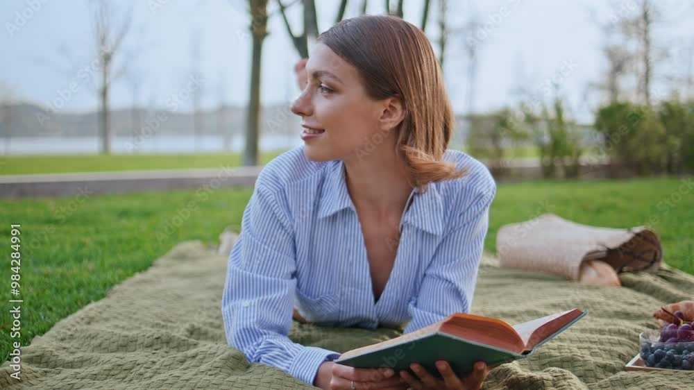 Serene woman relaxing book on park green grass smiling and looking away closeup. Serene woman relaxing book on park green grass smiling and looking away closeup.