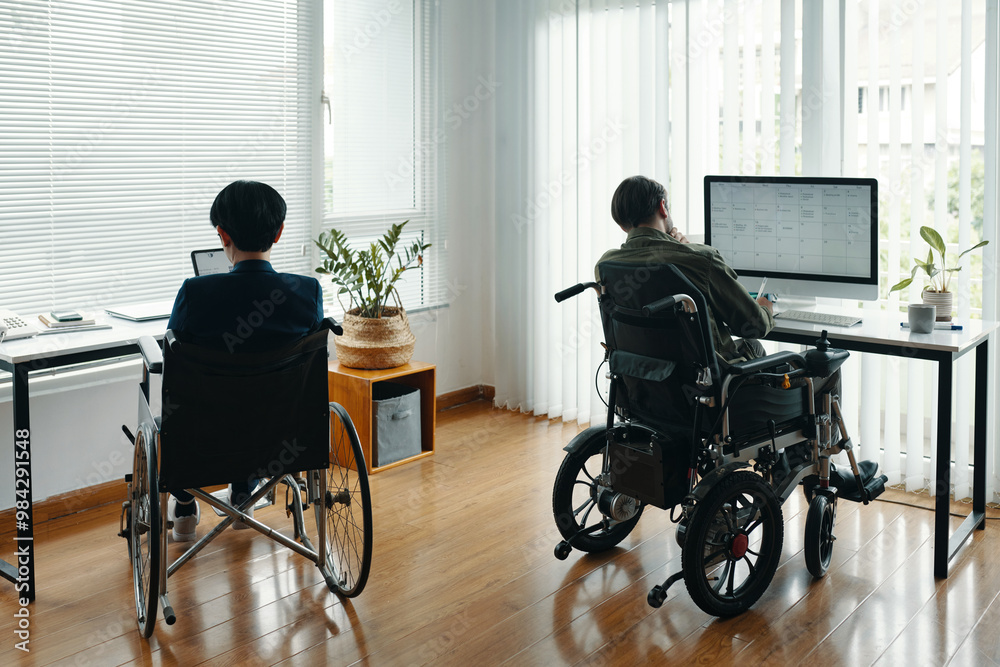 Rear view of business people with disability working on computers in their workplaces in office Rear view of business people with disability working on computers in their workplaces in office
